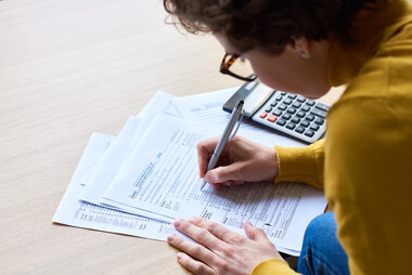 Adult filling out paper tax forms for filing income taxes