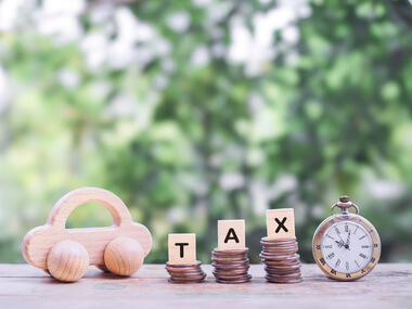 Wooden car, coin stacks labeled T, A, X, and a stopwatch arranged on a table